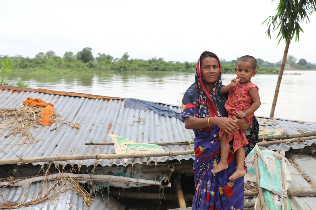 Khadija con il figlio di fronte alla loro casa, sommersa dalle alluvioni. Foto: Mutasim Billah/Oxfam 