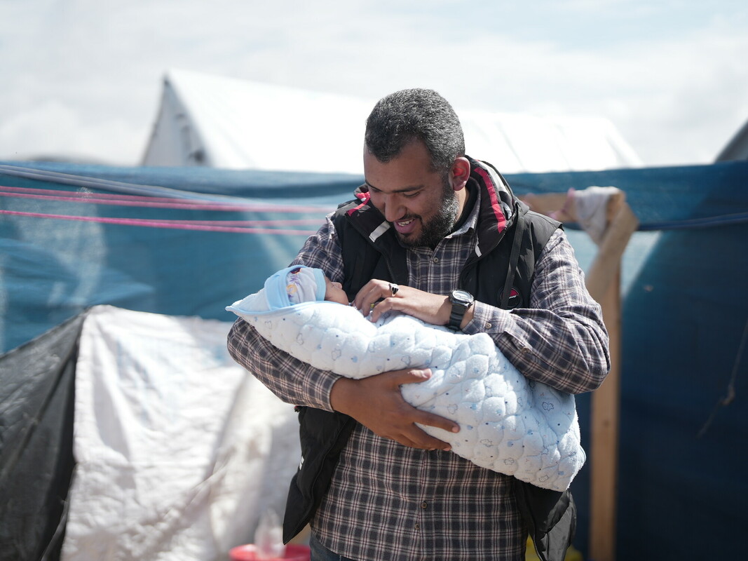 Fedaa tiene in braccio il suo bambino appena nato nella sua tenda a Tal Sultan a Rafah. Il suo bambino è nato in una tenda dopo che Fedaa ha perso la casa e la fabbrica.