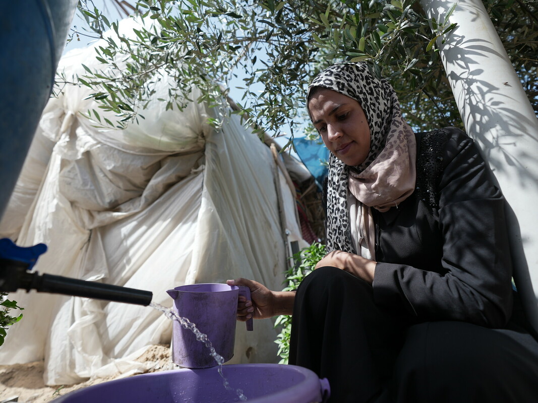 Wafa attinge dell’acqua a una cisterna installata da Oxfam nel campo di Al-Mawasi, in cui si sono rifugiate migliaia di persone. Foto: Alef Multimedia/Oxfam 