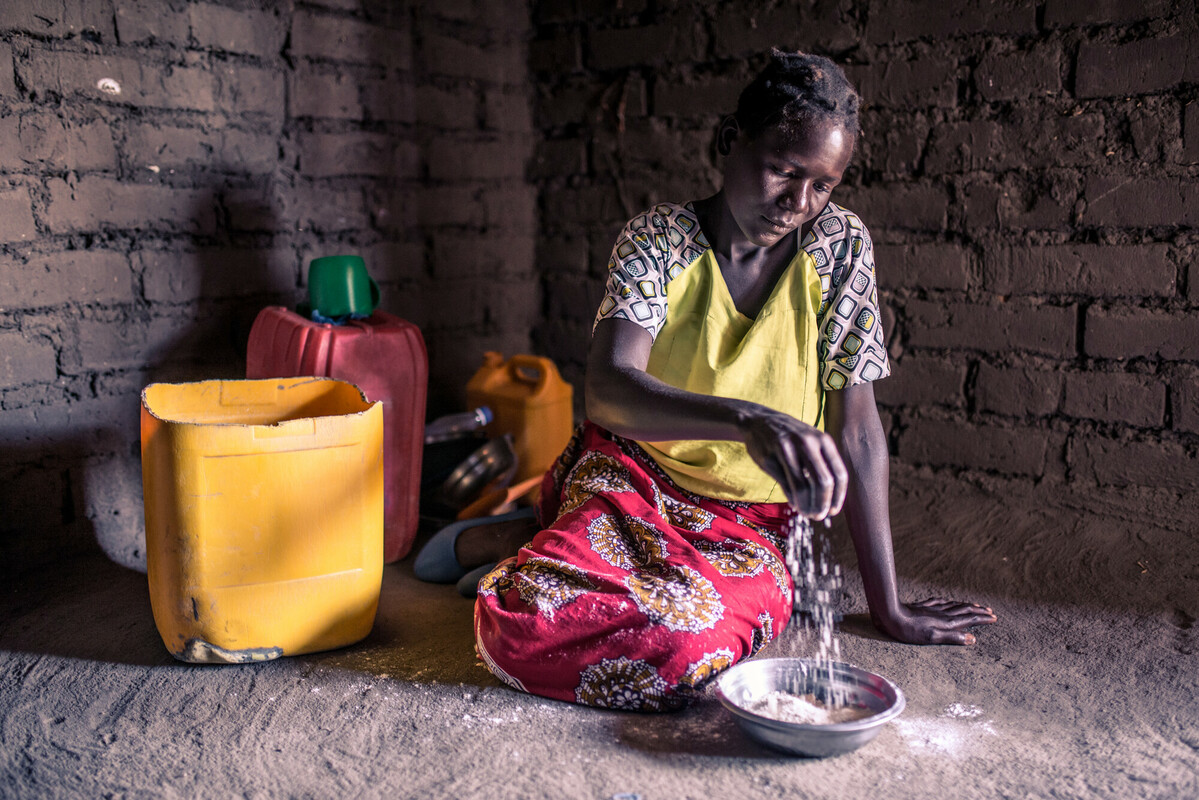 Blantyre Rural, Malawi: Elube (32) è seduta in casa sua mentre raccoglie piccole quantità di farina di mais in una ciotola. La famiglia di Elube è stata gravemente colpita dalla siccità e sta affrontando carenze alimentari a causa di un raccolto scarso.